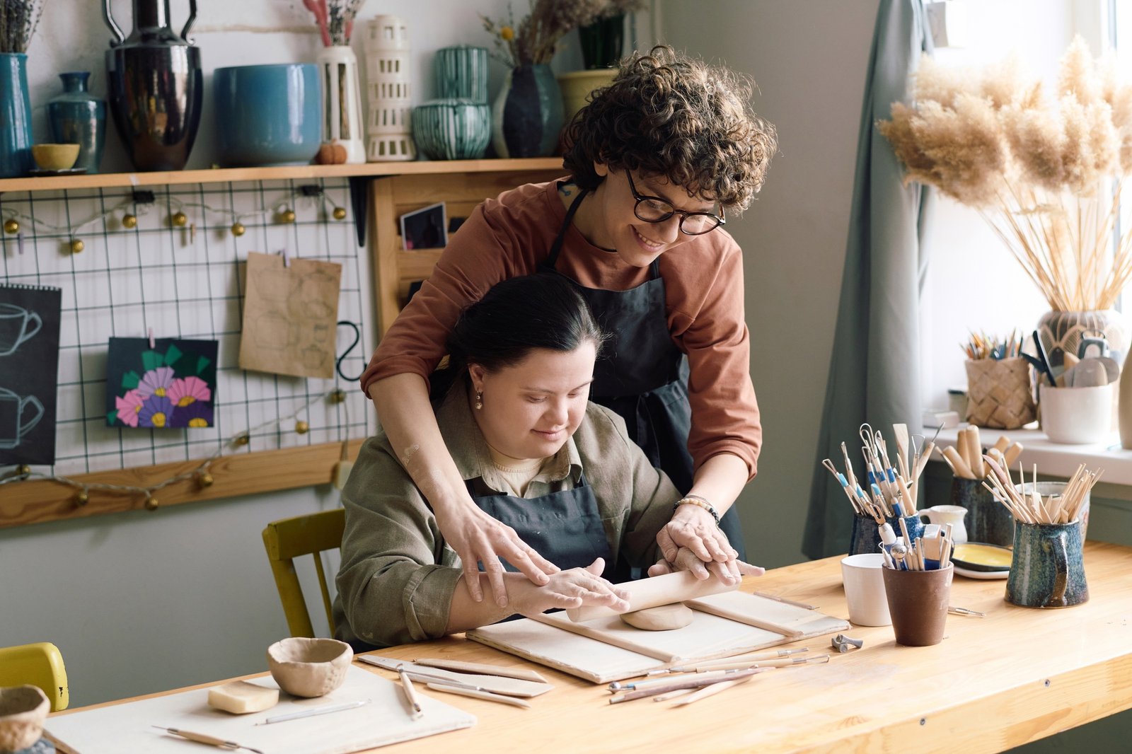 Artisan And Girl With Disability Rolling Out Clay